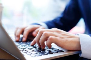 Hands typing on laptop keyboard