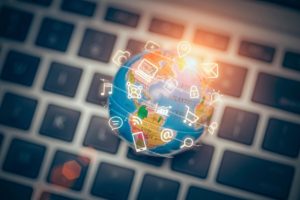 Globe with digital icons on laptop keyboard