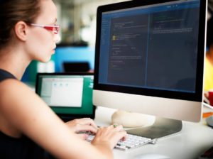 Female developer coding on desktop computer